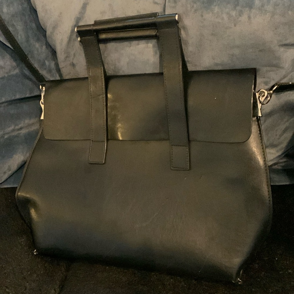 Black handbag w/ flap over a zipper close interior. Handles & a removable strap.